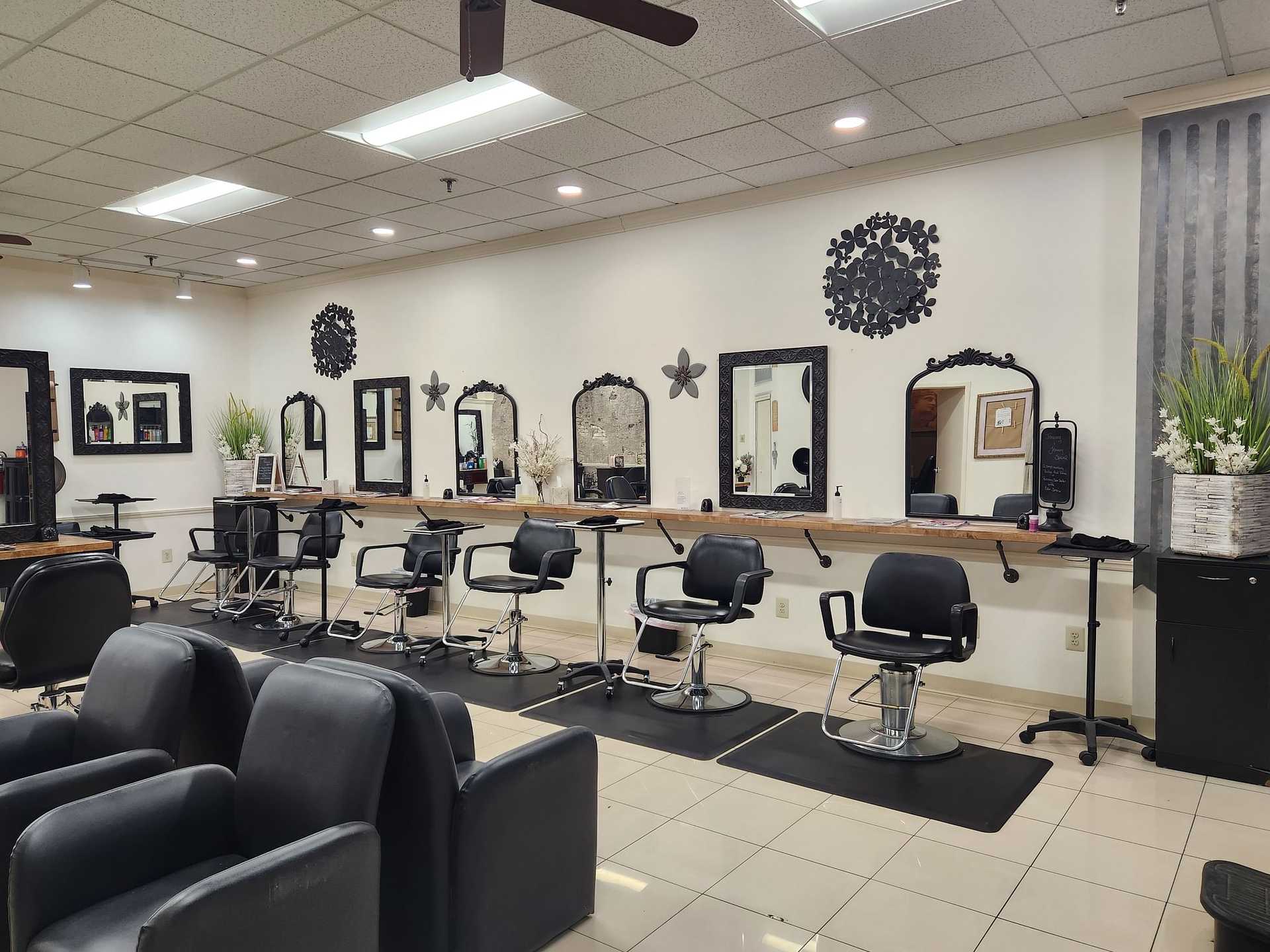 Spacious, modern hair salon with multiple styling stations, black chairs, and decorative mirrors.