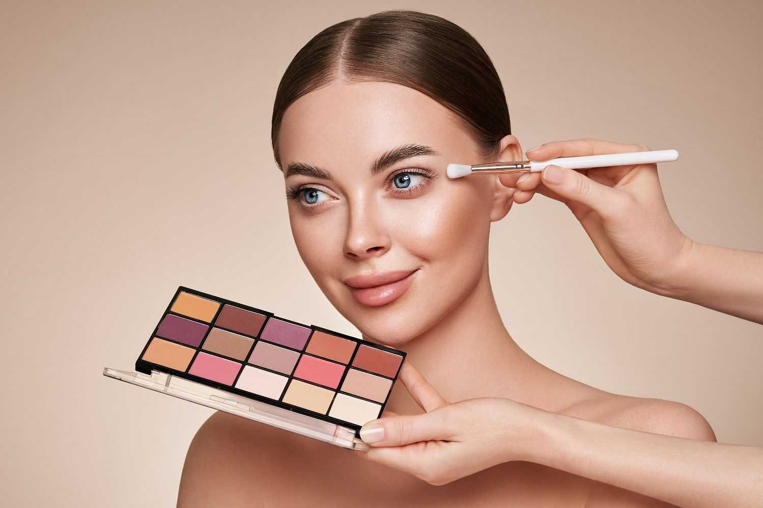Woman getting eyeshadow applied with makeup palette and brush.