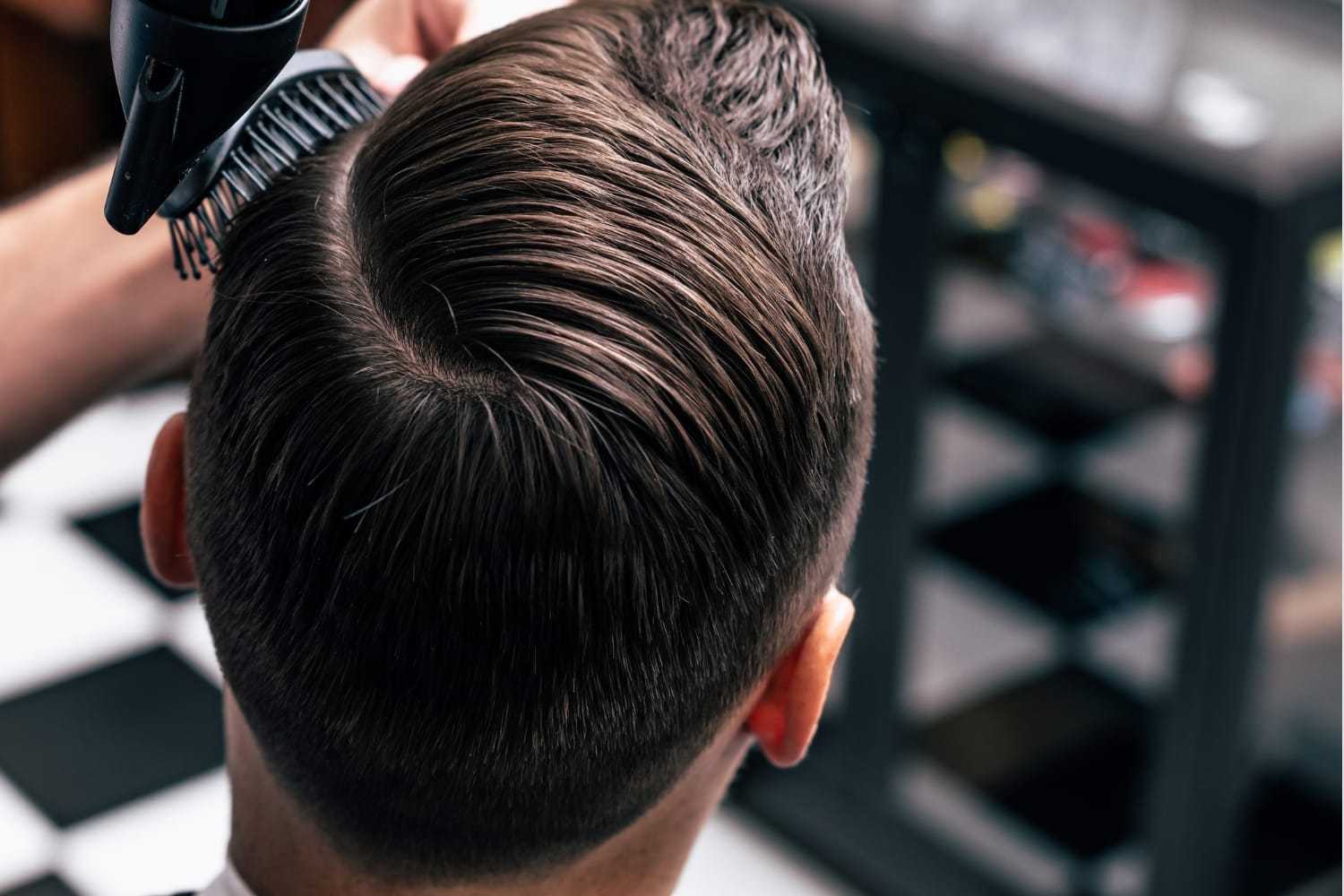 Man getting a modern haircut in a barbershop, showcasing a neatly styled back view of his hair.