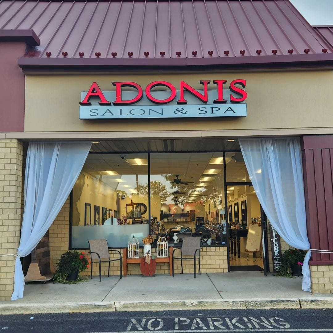 Front view of Adonis Salon & Spa with window displays and outdoor seating. Sign reads "No Parking.